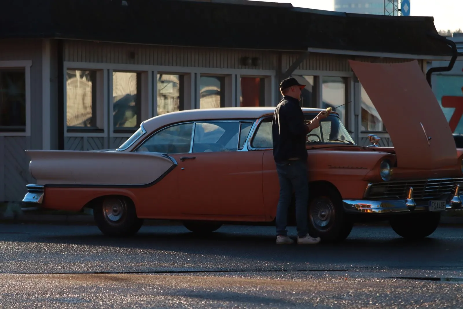 Voiture de collection exposée pour la vente, capot ouvert et panneau de prix près d'un atelier